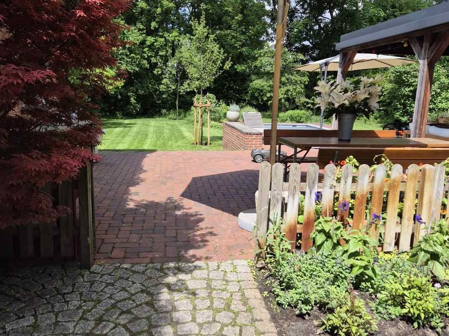Terrasse mit Sonnenschirm und gepflegtem Beet